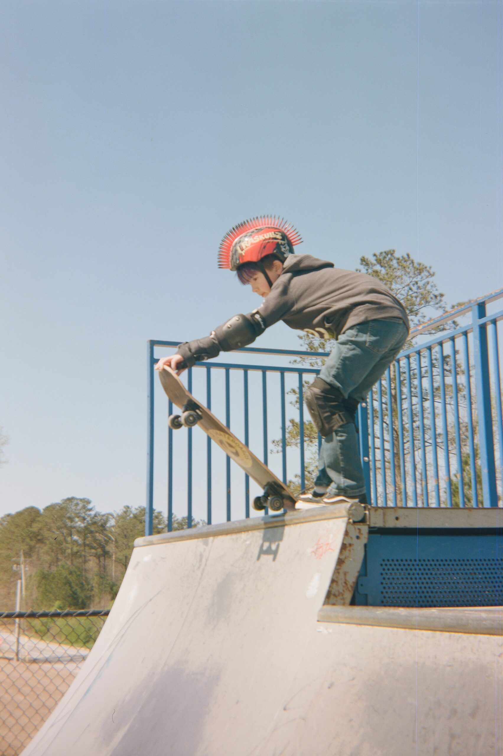 Little boy with a skateboard posed at the top of a half-pipe