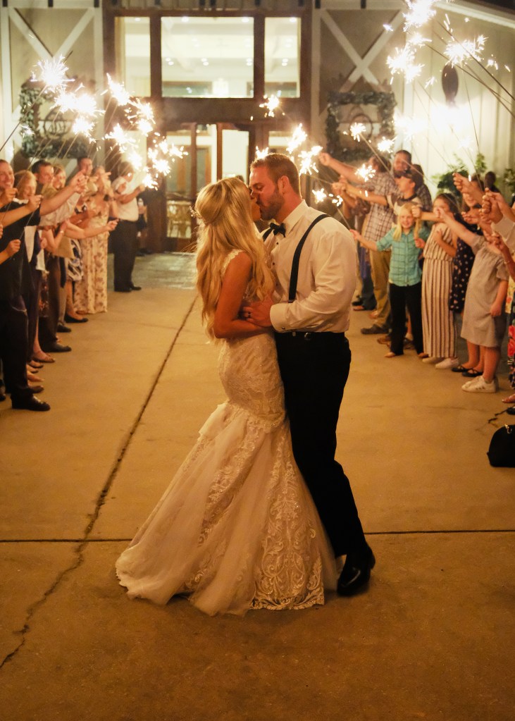 a couple kissing in front of a wedding venue in Newnan, Georgia, standing under lit sparklers